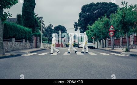 People in bacteriological protection suits walking down an empty street Stock Photo