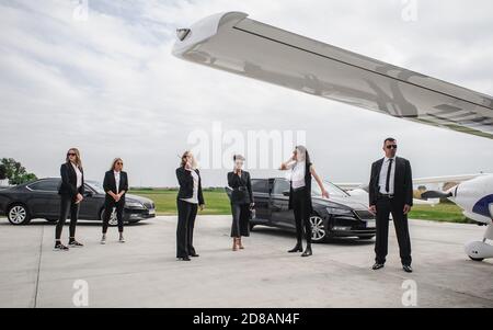 Famous female celebrity with bodyguards surrounded. VIP security agents and close protection officers Stock Photo