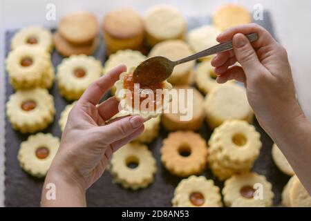 Woman making traditional german spitzbuben weihnachtskekse linzer biscuit cookies filled with marmalade Stock Photo