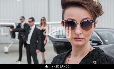 Famous female celebrity with bodyguards surrounded. VIP security agents and close protection officers Stock Photo