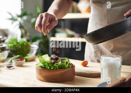 Close-up of chef putting fried meat on the plate with vegetables he cooking dish from chef Stock Photo