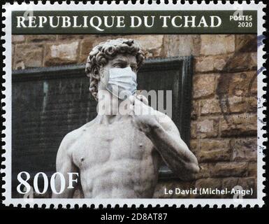 David by Michelangelo with antivirus mask on postage stamp. Image of the statue wearing the mask. Stock Photo