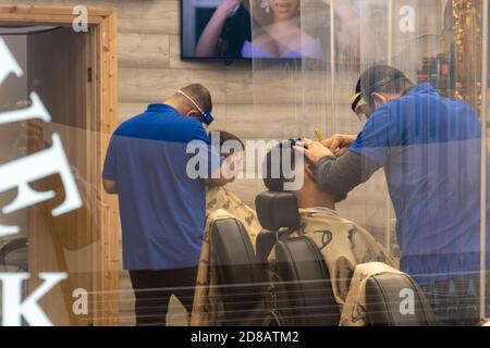 Barbers working with covid-safe business precautions wearing face shields during the covid-19 coronavirus 2020 pandemic, UK. The new normal. Stock Photo