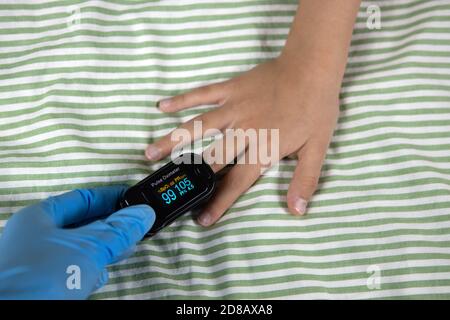 Doctor measures pulse rate, oxygen on finger of kid with pulse oximeter, close-up. Normal saturation level, high pulse. Health care, preventive measur Stock Photo