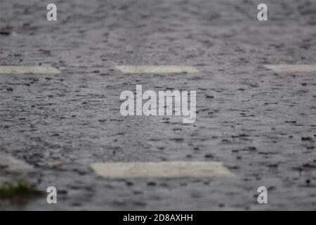 Rain on dark grey a asphalt road with white road marking Stock Photo