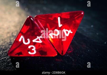 Close up of two red 4 sided dice on a dark slate surface. Stock Photo