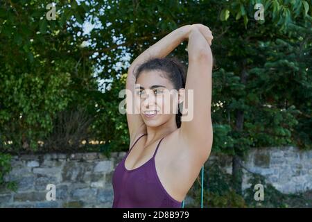 Young woman practicing calisthenic with an elastic band in a park Stock Photo