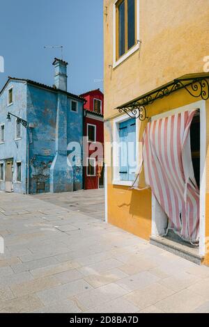 White and red striped curtain moved by the wind in Burano, Italy, on a sunny summer day Stock Photo