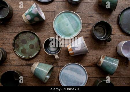 Selection of ceramic mugs, cups, and plates on wood surface Stock Photo
