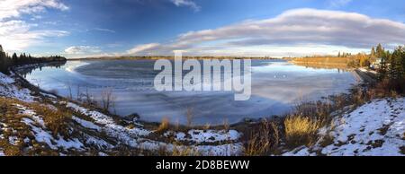 Panoramic Landscape Scenery of Glenmore Reservoir in South Calgary, Alberta with Lake surface water half frozen with city center skyline on horizon