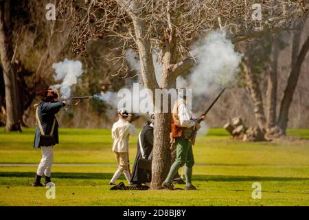 Rebel soldiers return musket fire at a historical reenactment of an American Revolutionary War battle in a Huntington Beach, CA, park. Stock Photo