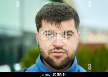 Serious young bearded man is walking outside at summer. Stock Photo