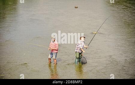 very long. father and son fishing. adventures. Big game fishing. male friendship. two happy fisherman with fishing rod and net. recreation and leisure outdoor. hobby and sport activity. Trout bait. Stock Photo