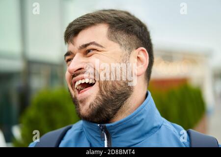 Handsome caucasian man with beard walks outdoors and smiles. Stock Photo