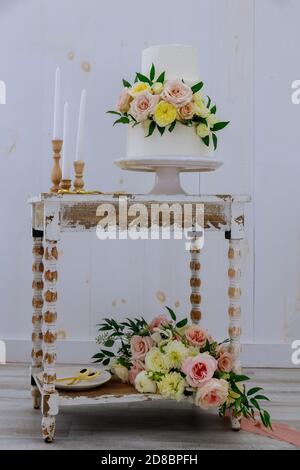 Rustic style wedding cake with fresh flower and candles on vintage table. Stock Photo