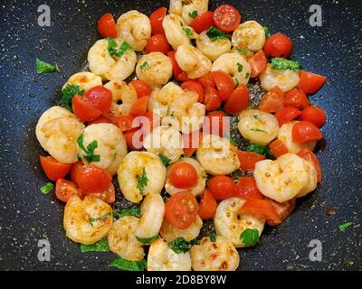 Delicious shrimp, tomatoes and parsley grilled on a pan. Tasty traditional homemade seafood. Stock Photo