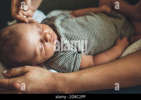Upper view photo of acaucasian mother looking at her daughter sleeping well and touching her small infant face Stock Photo