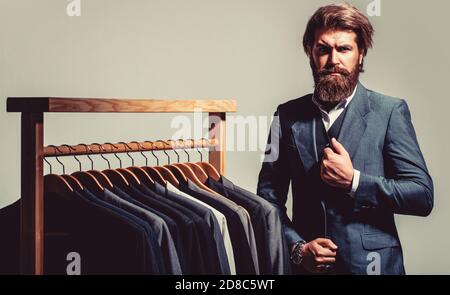 Male suits hanging in a row. Men clothing, boutiques. Tailor, tailoring. Stylish men's suit. Man suit, tailor in his workshop Stock Photo