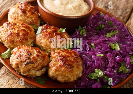 Fried Danish meatballs with hot stewed red cabbage and sauce close-up in a plate on the table. horizontal Stock Photo