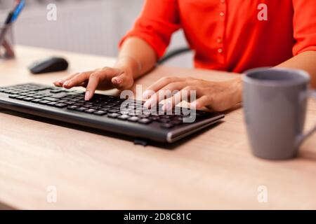 Unrecognizable businesswoman entrepreneur typing finance communcation in workplace. Busy successful employee sitting at table in workplace working on important financial project. Stock Photo