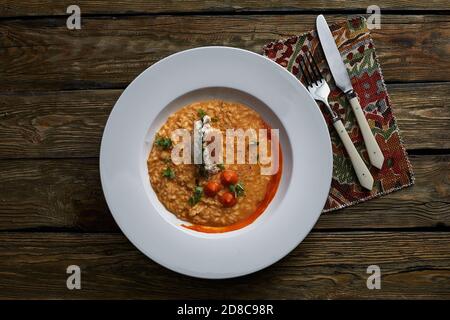 Italian cuisine. Plate of tomato risotto, olive oil and cherry tomatoes on wooden background Stock Photo