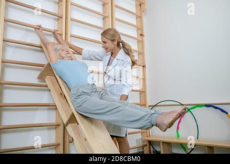 Old woman exercising in a rehabilitation center with instructor Stock Photo