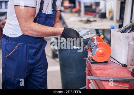 Male worker using grinding machine in garage Stock Photo