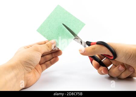 Man cuts paper with stationery scissors on white isolated background Stock Photo