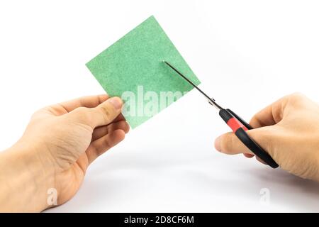 Man cuts paper with stationery scissors on white isolated background Stock Photo