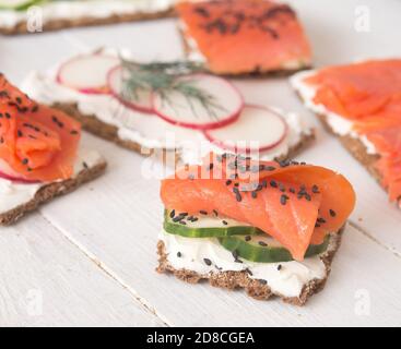 Canapes and sandwiches with salmon and vegetables on wooden background Stock Photo