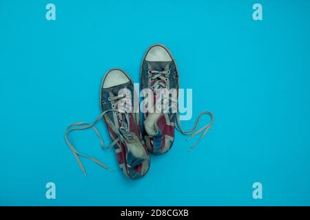worn out and dirty gumshoes isolated on blue background. Top view and copy space. Stock Photo