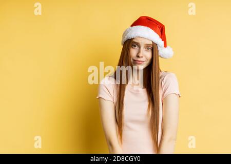 Caucasian freckled redhead woman making praying gesture, asking boyfriend with pleading look to fulfill her dream, to buy gift over yellow background. Stock Photo