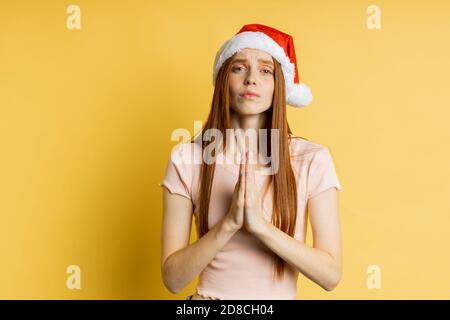 Caucasian freckled redhead woman making praying gesture, keeping palms together, asking boyfriend with pleading look to fulfill her dream, to buy gift Stock Photo