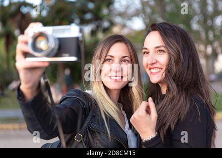 Close up of two smiling women with an analog camera in their hands. Stock Photo