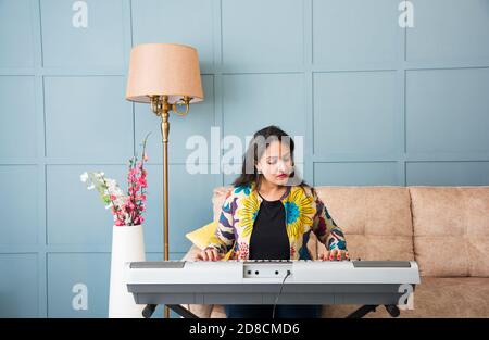 Pretty Asian Indian young woman musician performing while taking online music class or recording video on smartphone Stock Photo