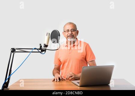 Confident Indian old man speaking in recording mic with filter while recording a video blog for his subscribers, looking at camera Stock Photo