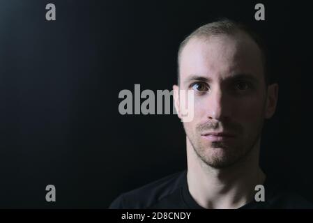 Beautiful and dramatic male portrait of handsome young man on black background using light splitting technique, Dublin, Ireland Stock Photo
