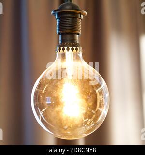 round incandescent lamp hanging on brown blurred background Stock Photo