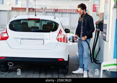 South asian man or indian male refueling his white car on gas station. Stock Photo