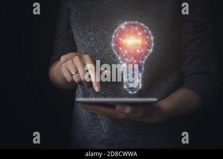 Hand holding tablet with drawing light bulb. Close up, idea concept with innovation and inspiration