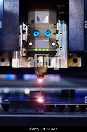 Laser cut head machine while cutting the sheet metal with the sparking light in factory Stock Photo