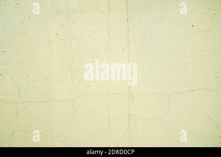 Old cracked light yellow colored concrete wall, weathered building background. Stock Photo