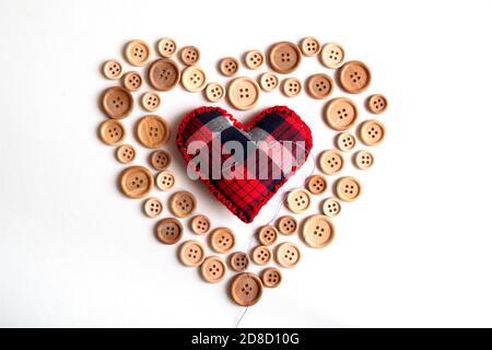 top view of buttons and needle pillow on heart form on white background, St. Valentine's day concept Stock Photo