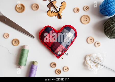 sewing kit with thread, scissors, buttons and needle pillow on white background, flat lay Stock Photo