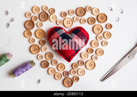 flat lay of sewing kit with buttons and needle pillow on heart form on white background, St. Valentine's day concept Stock Photo