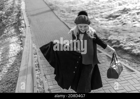 a woman walks up the stairs and in burgundy. Black and white palette and biret, looking at the camera in black clothes, in the fall against a Stock Photo