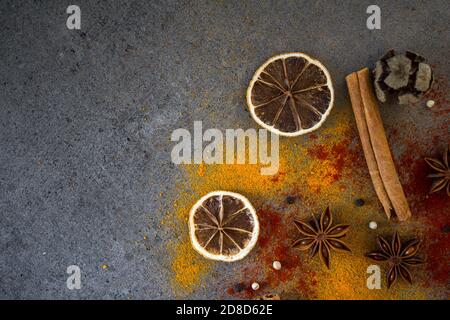 Different spices on a table. Top view photo of cinnamon, curcuma, lemon, anise and paprika. Gray background with copy space. Stock Photo