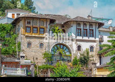 Gjirokaster town/ Albania – August 2, 2020: traditional architecture – old house with gray stone roof and arched windows. Summer cityscape of historic