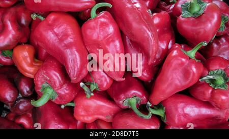 Close up of red bell peppers on a counter in the supermarket. A large number of red peppers in a pile Stock Photo