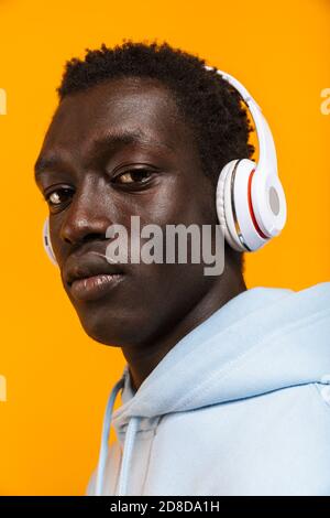 Image of young african american guy in headphones looking at camera isolated over yellow background Stock Photo
